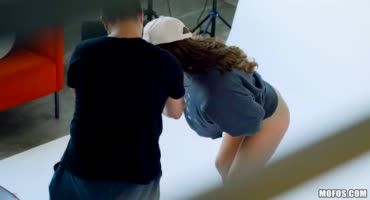 В студии фотосъемки паренёк бдит за фотомоделью и распускает руки